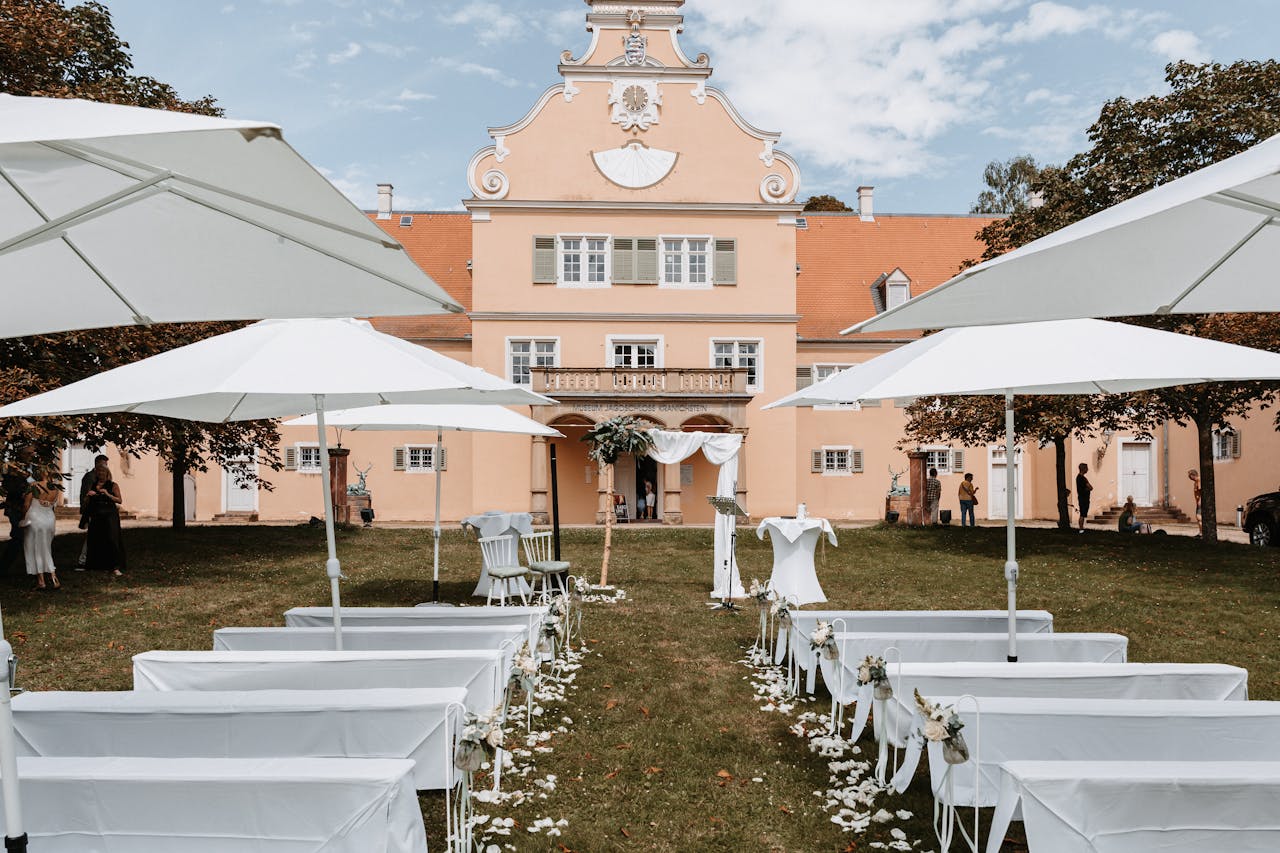 Stunning outdoor wedding scene with elegant white decor and a historic backdrop under clear skies.
